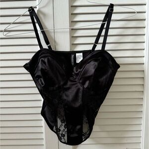 Black corset with lace and a bow detail, adjustable straps